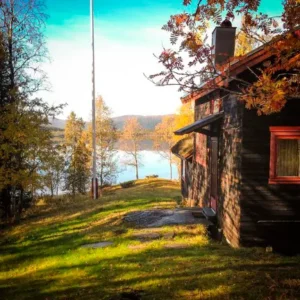 Sidan av fjällstugan med en äng ner mot en fjällsjö